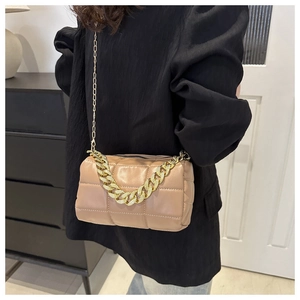 Detail of beige quilted square crossbody bag with decorative gold chain and metal strap