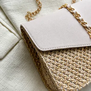 Detail shot of neat stitching on leather flap and woven straw texture with gold chain