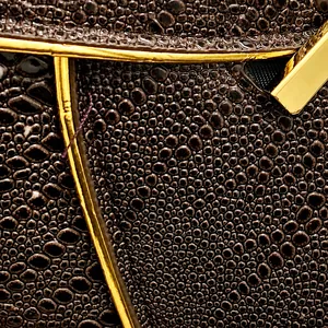 Detail shot of brown ostrich-textured leather and elegant gold metallic trim details