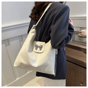 Détail d'un sac hobo crème avec boucle de nœud argenté et bandoulière en chaîne