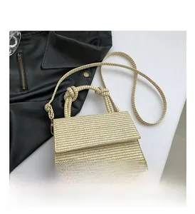 Close-up of cream woven texture and knotted top handle on the small square flap bag