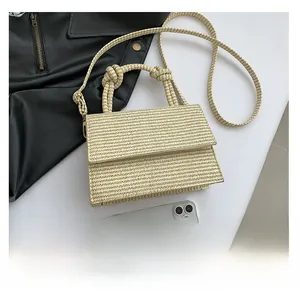Detailed close-up of a mini straw handbag with a knotted handle and woven texture