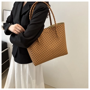 Detalle de un bolso tote marrón grande con estampados geométricos llevado por una modelo