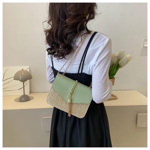 Détail du sac en paille tissé avec rabat en cuir vert et chaîne à pompon dorée