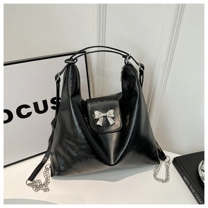 Détail du sac hobo noir en cuir synthétique brillant avec nœud argenté et chaîne