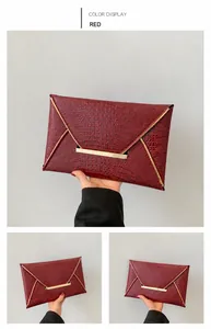 Detailed close-up of red crocodile embossed envelope clutch with elegant gold metal trim