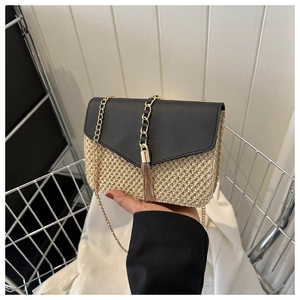 Détail d'un sac en paille tressée avec rabat en similicuir noir et pompon doré