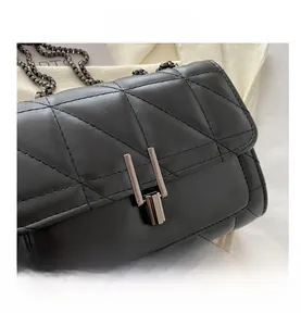 Détail d'un sac bandoulière noir matelassé avec boucle métallique et chaîne