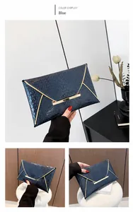 Detail of blue crocodile pattern envelope clutch with elegant gold metal trim and buckle