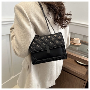 Bolso acolchado negro con cadena para mujer lucido por modelo con hebilla de metal