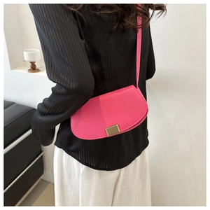 Detailed view of magenta faux leather saddle bag with gold metal clasp on model