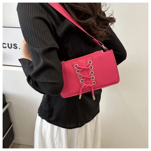 Détail du sac bandoulière fuchsia avec œillets argentés porté par un mannequin femme