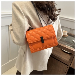 Detalle de bolso acolchado de cuero naranja brillante con cadena y hebilla metálica negra