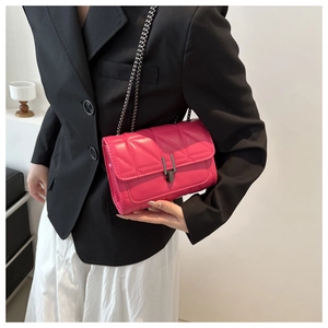 Détail d'un sac en cuir matelassé fuchsia avec chaîne en métal sombre et fermoir rectangulaire