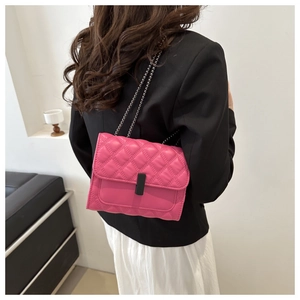 Bolso bandolera rosa acolchado con cadena de plata sobre una americana negra