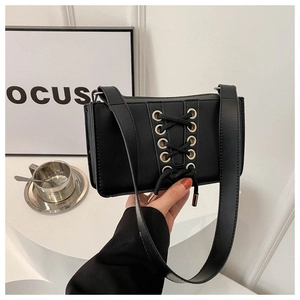 Détail d'un sac rectangulaire noir avec laçage unique et œillets argentés