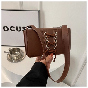 Détail du sac à bandoulière en similicuir marron foncé avec décor de nœud à lacets