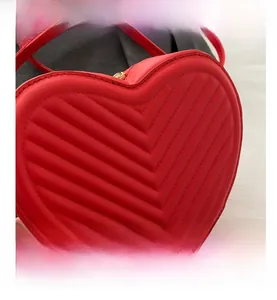 Détail du sac bandoulière rouge en forme de cœur avec motif matelassé en V et fermeture