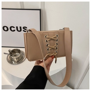 Détail du sac bandoulière avec laçage style corset et œillets métalliques argentés