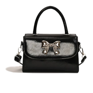 Sac à main noir brillant avec boucle nœud argenté et bandoulière réglable sur fond blanc