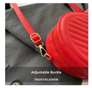 Détail du sac matelassé rouge avec boucle dorée réglable et fermeture éclair