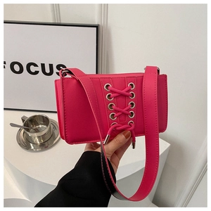 Détail du sac à bandoulière rose fuchsia avec lacets et œillets métalliques argentés