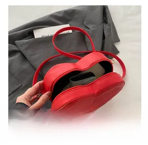 Vue détaillée de la capacité intérieure d'un sac rouge en forme de cœur avec un portefeuille