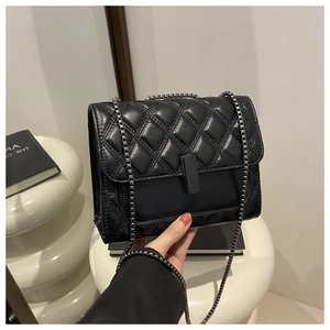 Detalle de bolso bandolera de cuero acolchado negro con cierre metálico y cadena