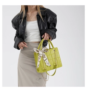 Detail der gelben Stepptasche mit goldener Kette und Seidentuch am Griff verziert