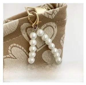 Detail of pearl handle and gold lobster clasp on heart-patterned canvas toiletry bag