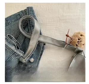 Détail du sac bandoulière argenté en similicuir avec bandoulière et ours en peluche