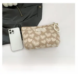 Detail of heart print cosmetic bag with pearl zipper showing large capacity with phone