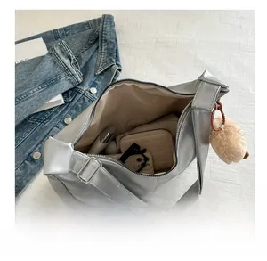 Vue intérieure montrant la grande capacité du sac hobo argenté avec des objets du quotidien