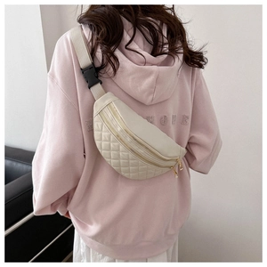 Close-up of beige quilted fanny pack with double zippers and wide fabric strap
