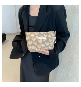 Detail of khaki heart pattern cosmetic bag with pearl handle and fashion bag patch