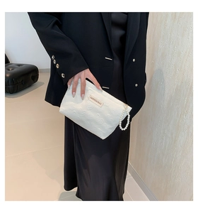 Detail of white canvas makeup bag with heart relief texture and pearl wristlet strap