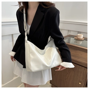Détail d'un grand sac hobo en cuir blanc brillant avec bandoulière réglable et zippée