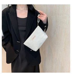 Detail of white heart-embossed pouch with pearl handle and Fashion Bag label