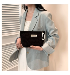 Chic black heart-textured makeup bag with white pearl wristlet held by a model