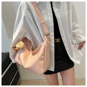 Détail du sac sous le bras en forme de croissant rose clair avec pendentif ours en peluche