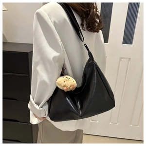 Détail du sac hobo en cuir PU noir brillant avec un pendentif ours en peluche tout doux