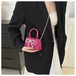 Detail of rose pink sequin mini bag with rhinestone bow and silver chain strap