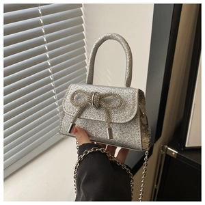 Detail of silver sequin mini bag featuring a rhinestone bow and metal chain strap