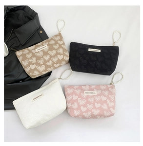 Detail view of heart embossed cosmetic bags in four colors with pearl handles