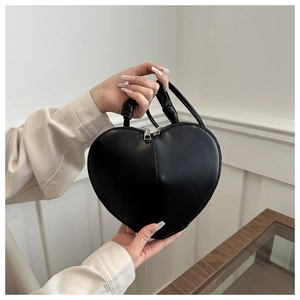 Detail of a black heart-shaped handbag with smooth leather texture and top handle