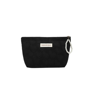 Black heart-embossed canvas makeup bag with pearl strap and fashion label on white background