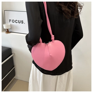 Detail of pink heart-shaped PU leather shoulder bag with decorative knotted strap details