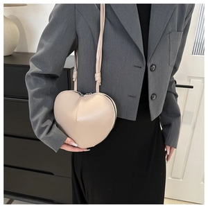 Detail of a beige heart-shaped leather crossbody bag styled with a grey blazer outfit