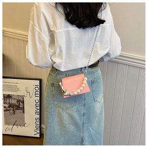 Détail du mini sac bandoulière rose avec chaîne argentée, perles et logo embossé