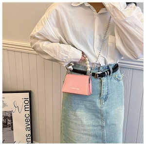 Mini sac bandoulière rose avec poignée en perles et chaîne porté par un mannequin en tenue